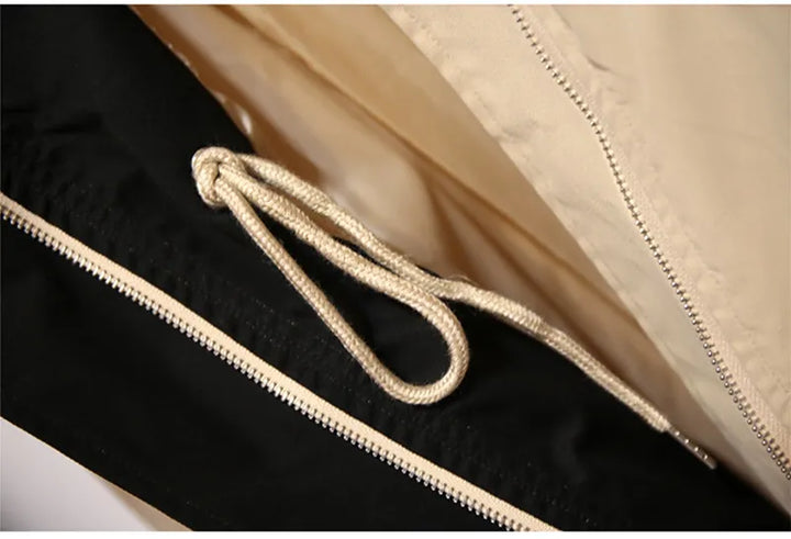 Beige und schwarze Jacke mit Reißverschluss und Kordelzug, modische Oberbekleidung.