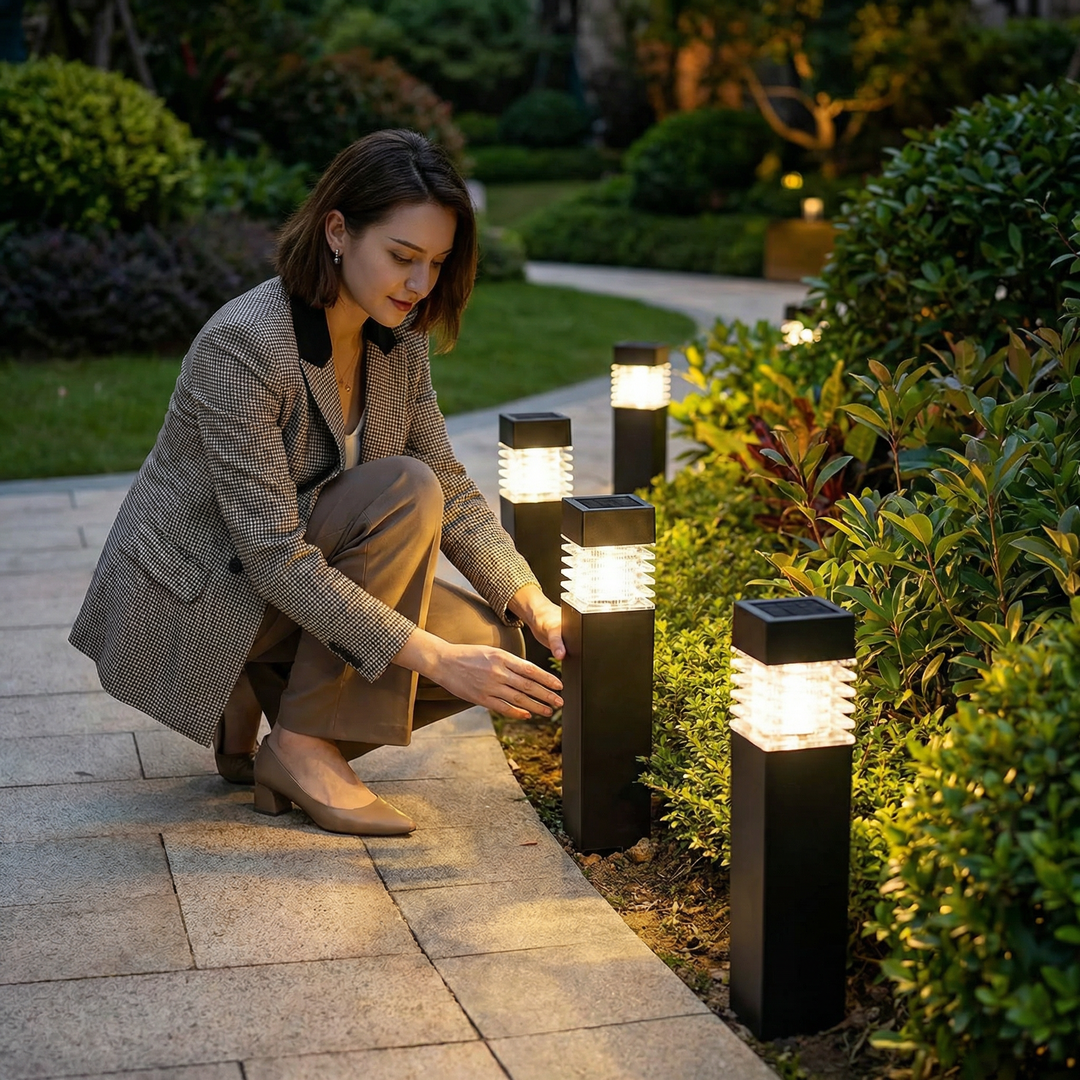 Black stake light among glowing lights along a paved garden walkway.