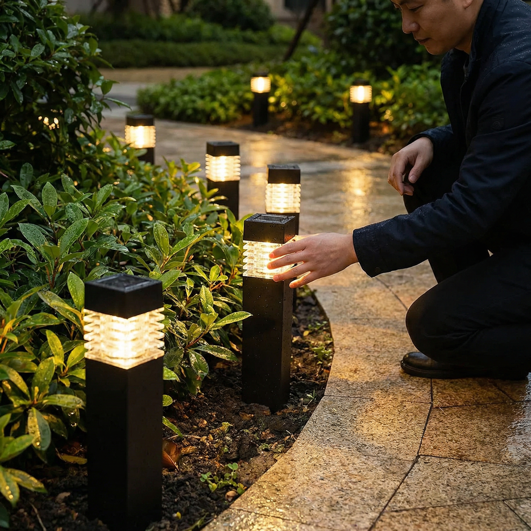 Black stake lights beside a wet garden path with raindrops on the dark posts.