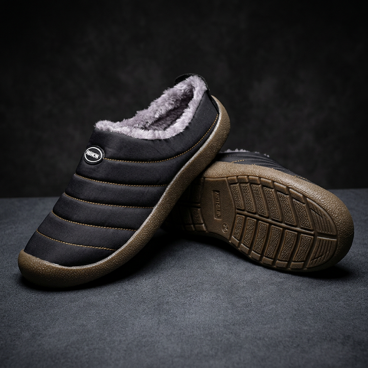 Black quilted slipper resting on its mate, which is flipped to display the anti-slip outsole 19