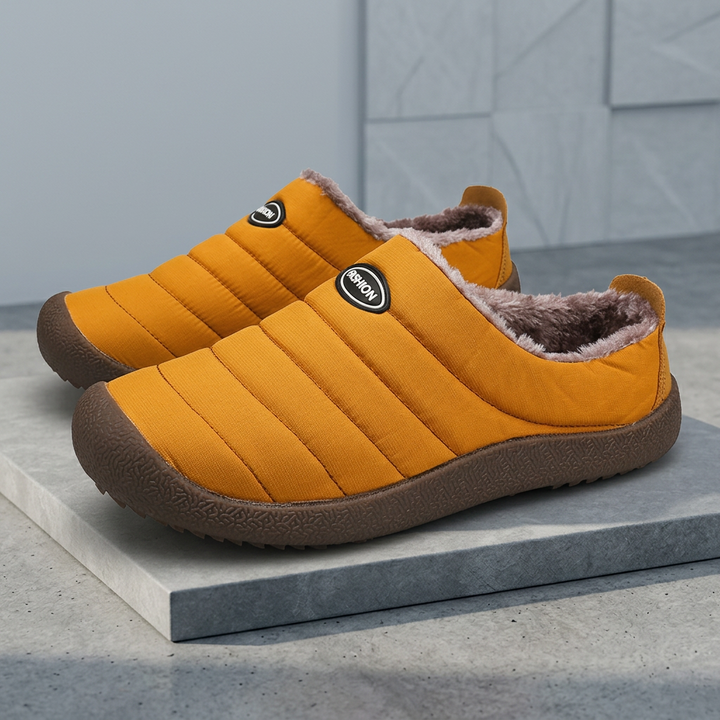Mustard orange quilted slippers with brown soles and plush lining on a gray slab in a styled setting 20