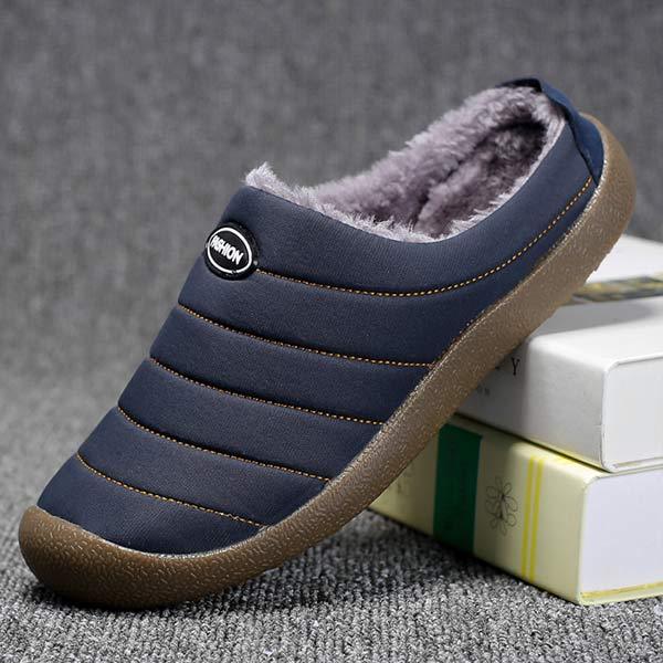 Navy blue slipper in side profile with orange stitching and fleece lining, propped on books 7