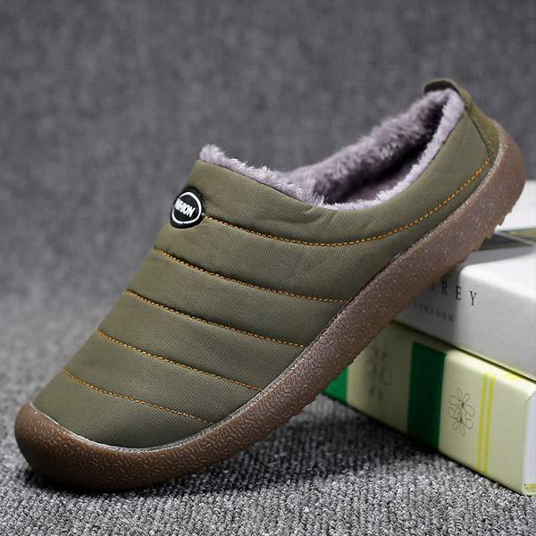 Single olive green slipper tilted against stacked books, showing quilted stitching and thick brown rubber sole 4