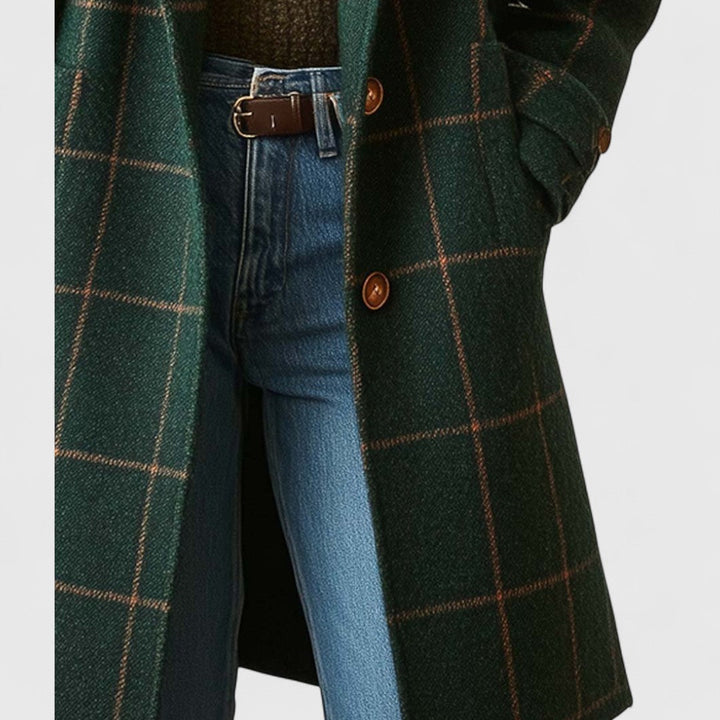 Women's plaid coat detail of the brown buttons and flap pocket, with a hand tucked in the pocket and jeans visible.