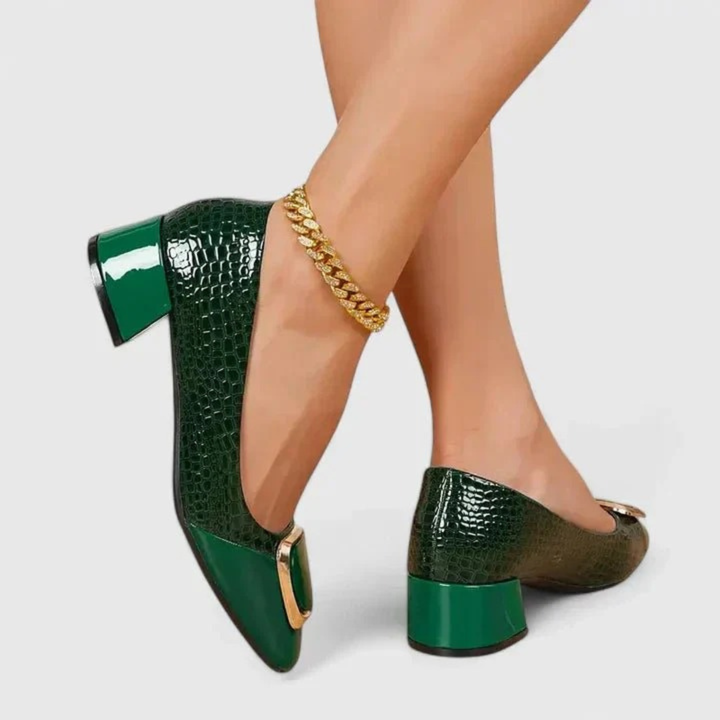 Model wearing the shoes in glossy dark green croc-embossed finish with gold buckle and block heel, another view.