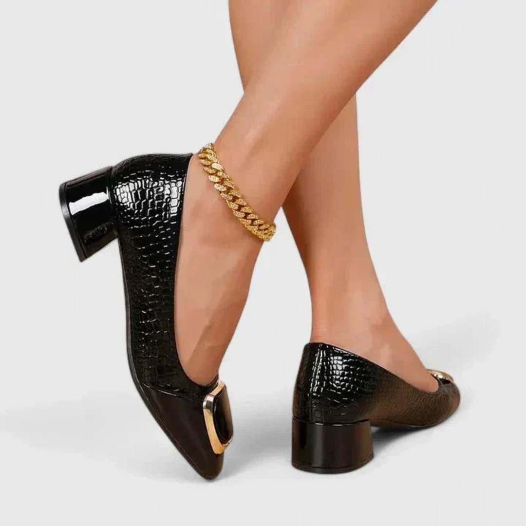 Model wearing the shoes in glossy black croc-embossed finish with gold buckle and block heel, another view.