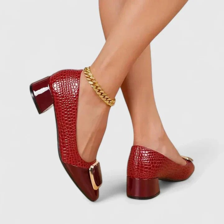 Model wearing the shoes in glossy red croc-embossed finish with gold buckle, another view.
