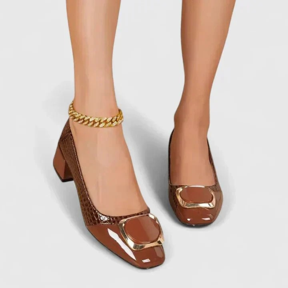 Model's feet wearing brown croc-embossed block-heel shoes with gold buckle, seen from the front.