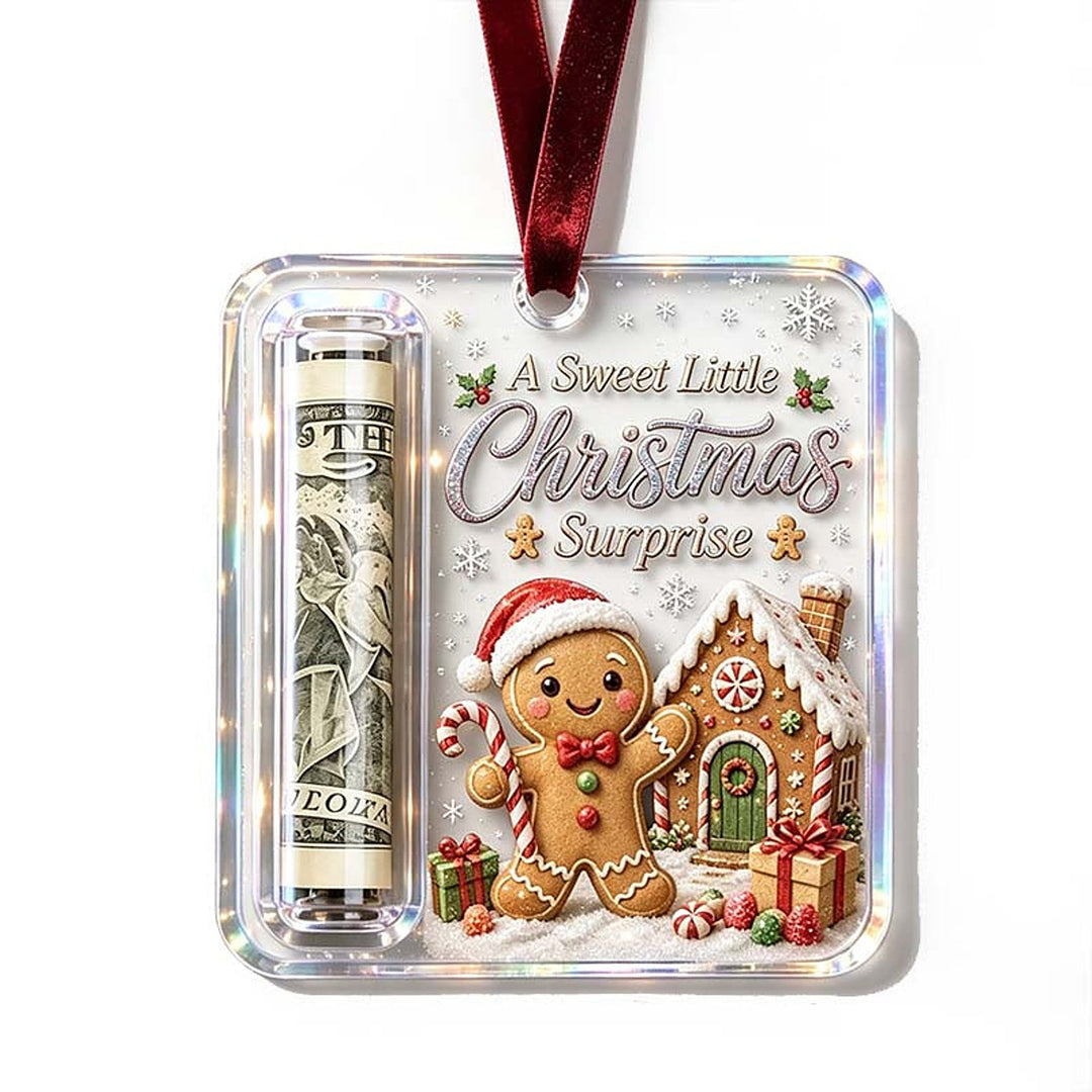 Gingerbread design ornament with a smiling gingerbread man in a Santa hat beside a candy-covered house and a rolled bill in the slot.