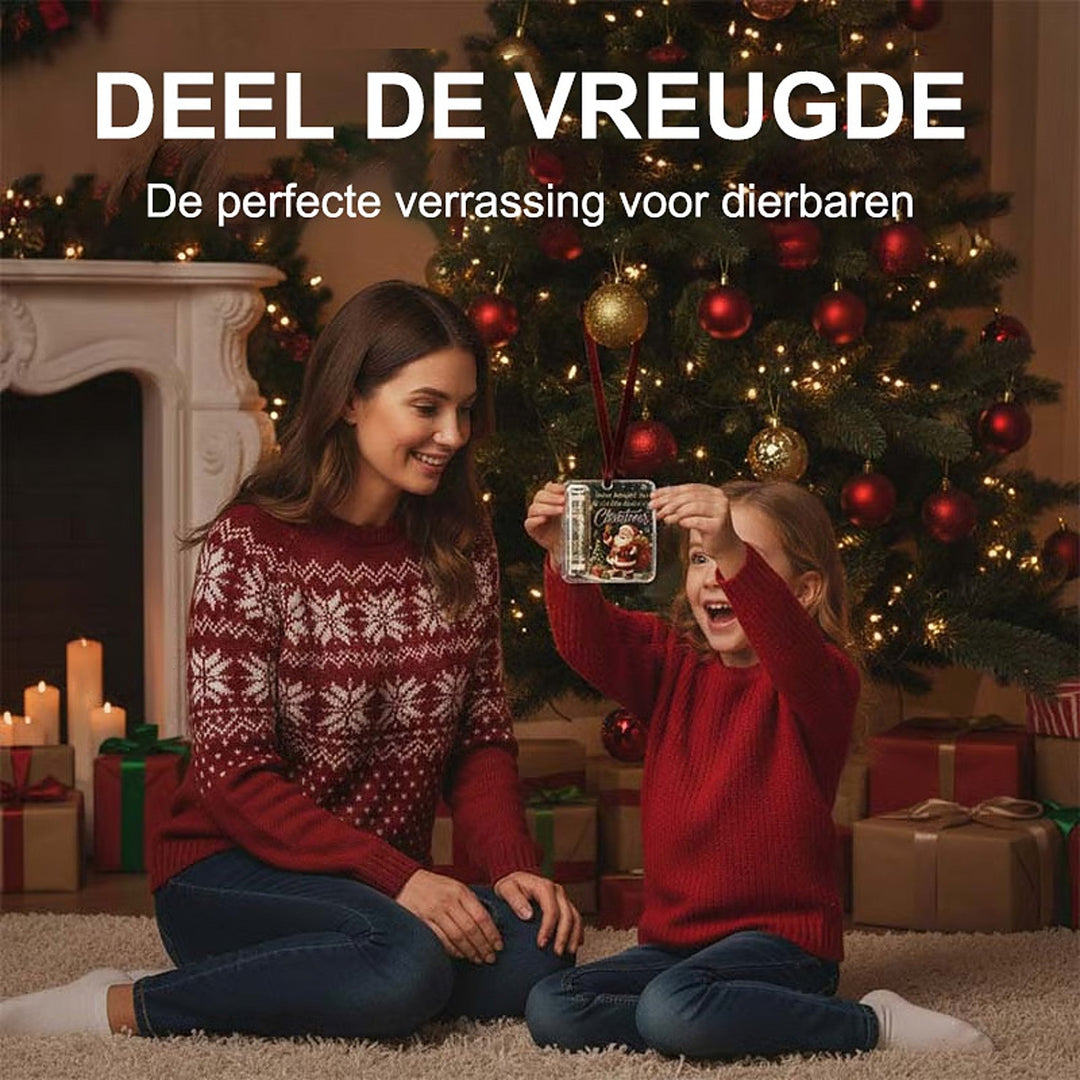 another view of a girl in a red sweater holding the hanging ornament in front of a Christmas tree.