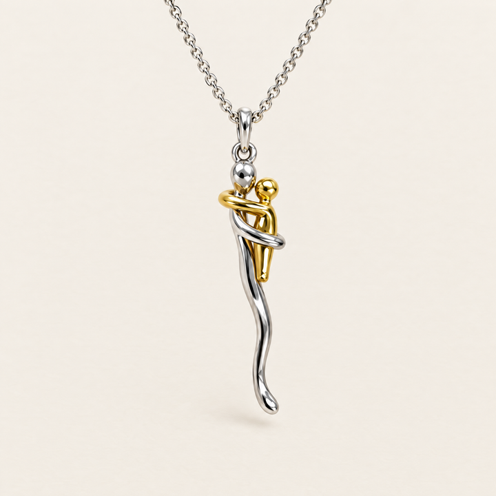 Hug pendant necklace in silver and gold tone shown front view on a cream background.