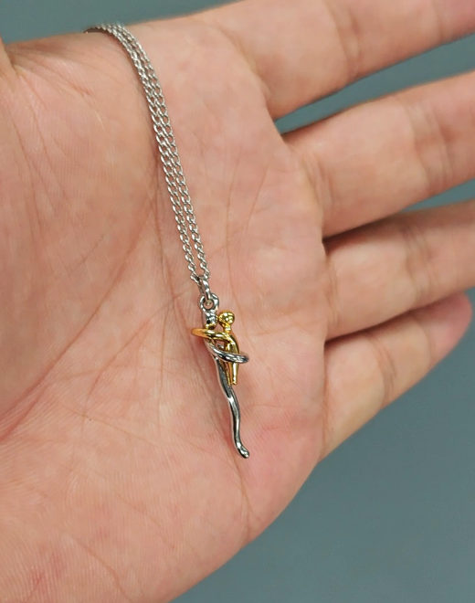 Hug pendant necklace and thin silver chain shown in an open palm, detail.