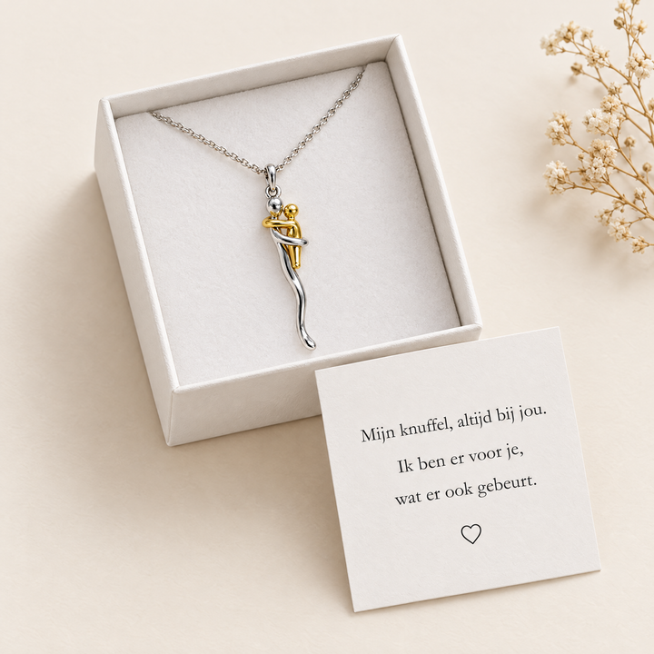 Hug pendant necklace in an open gift box with a card and dried flowers.