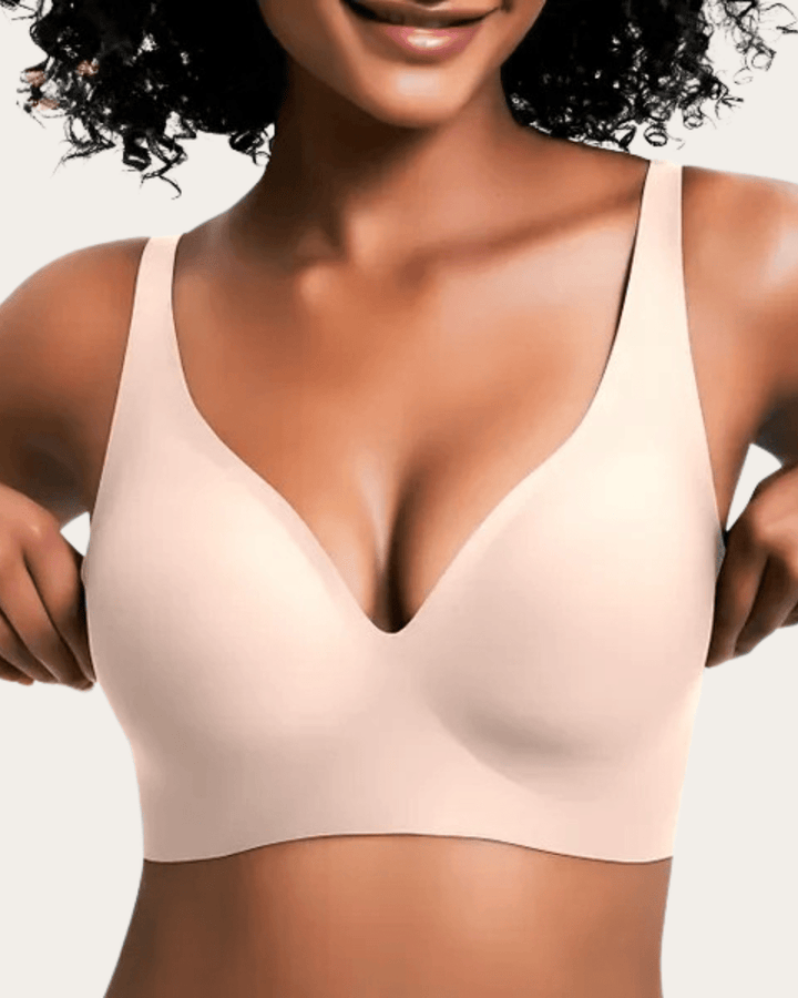 Model wearing the light beige seamless V-neck bra, adjusting the sides.