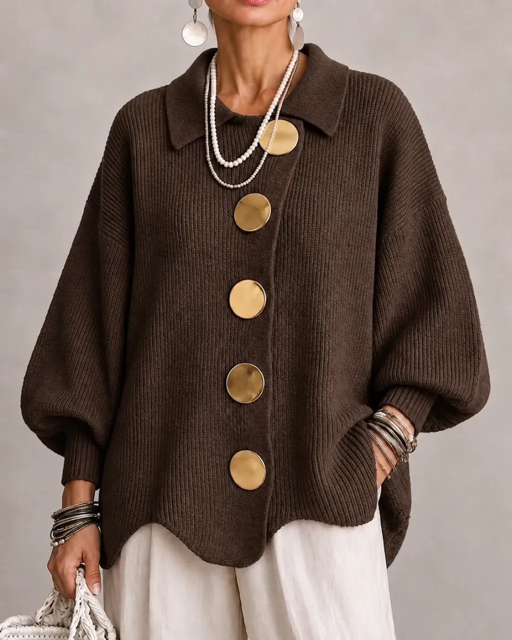 Dark chocolate brown ribbed cardigan worn open-collared with gold buttons, layered pearl necklaces and white pants. 9