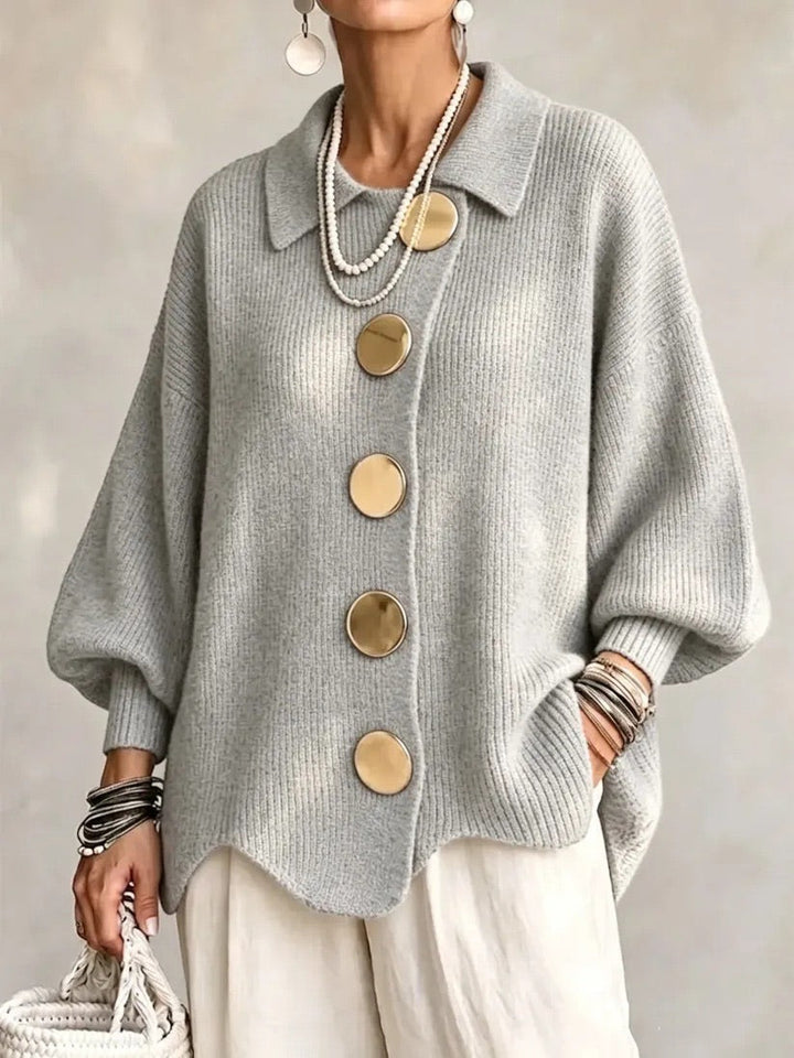 Light gray ribbed cardigan on a model, with gold buttons, scalloped hem and relaxed oversized sleeves. 10