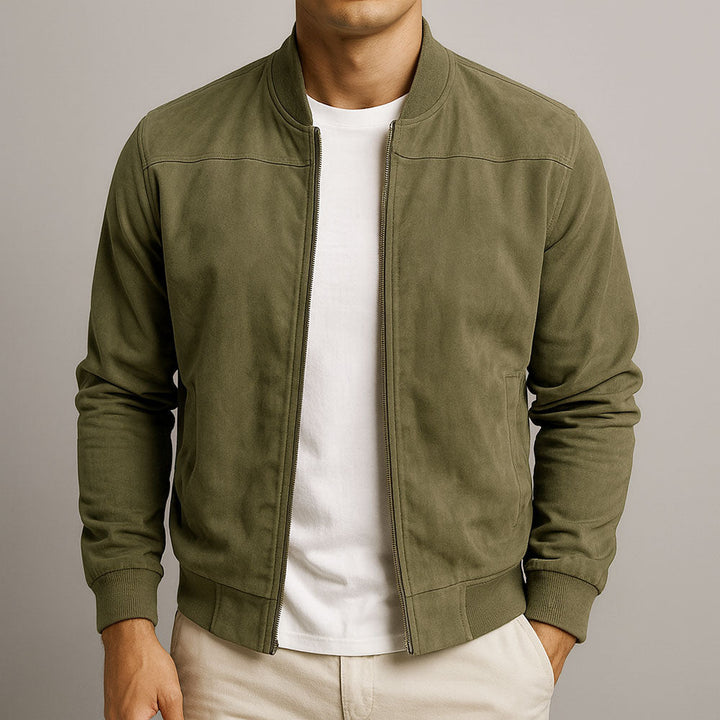 Front view of the jacket in olive green, worn unzipped over a white tee and cream pants with ribbed cuffs.