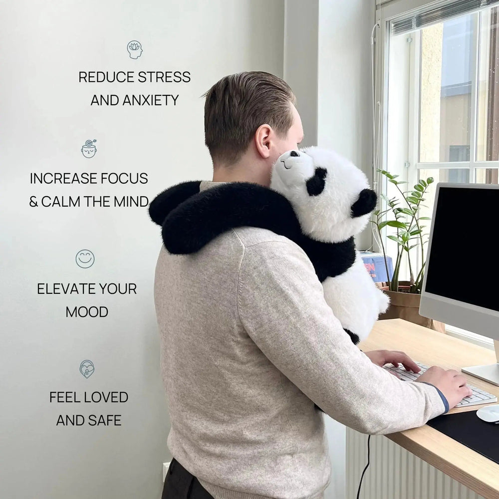 Man in a gray sweater typing at a standing desk with the panda draped over his shoulder, arms wrapped around his neck. 2