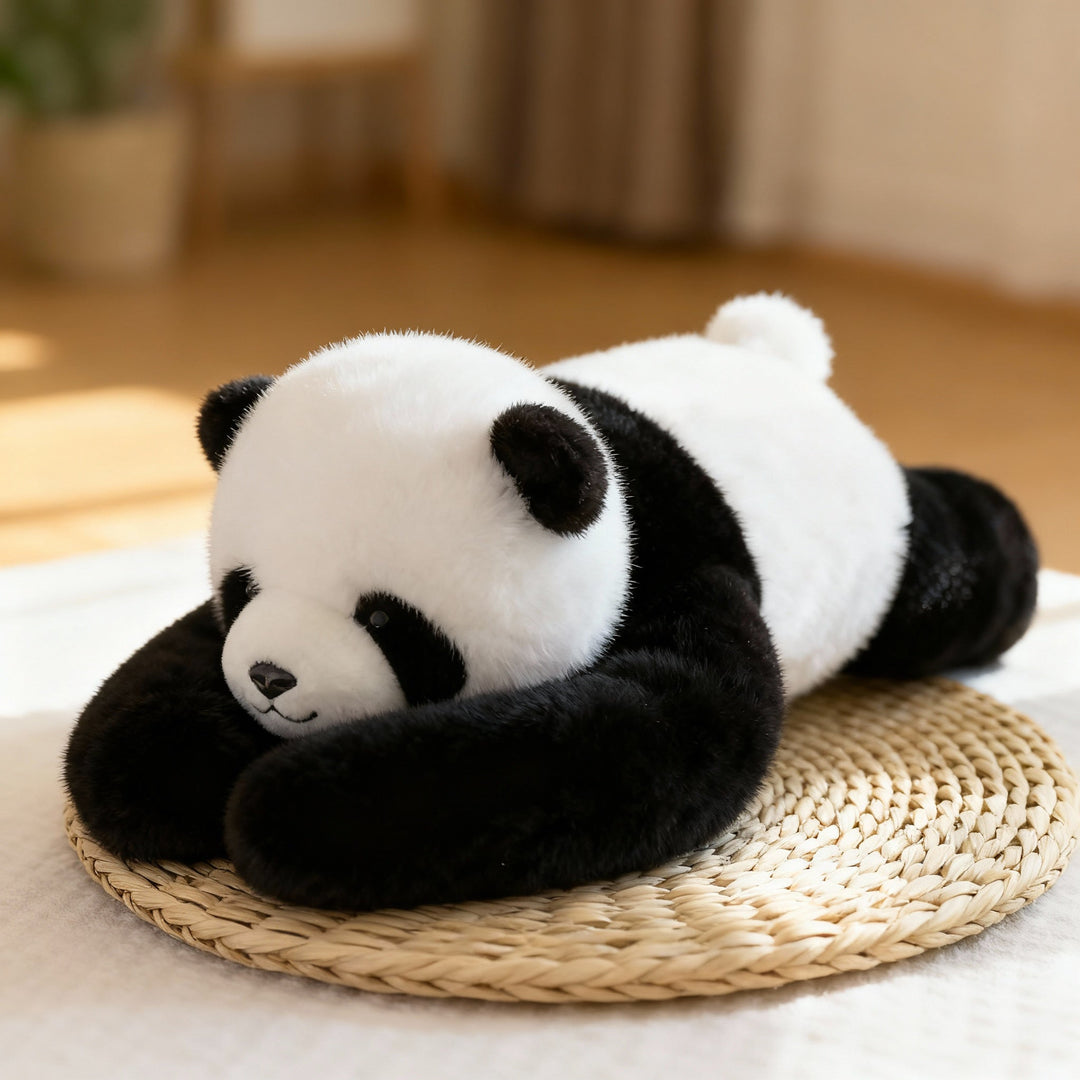 Black and white panda plush lying on a woven straw mat, its long black arms curled around its head. 1