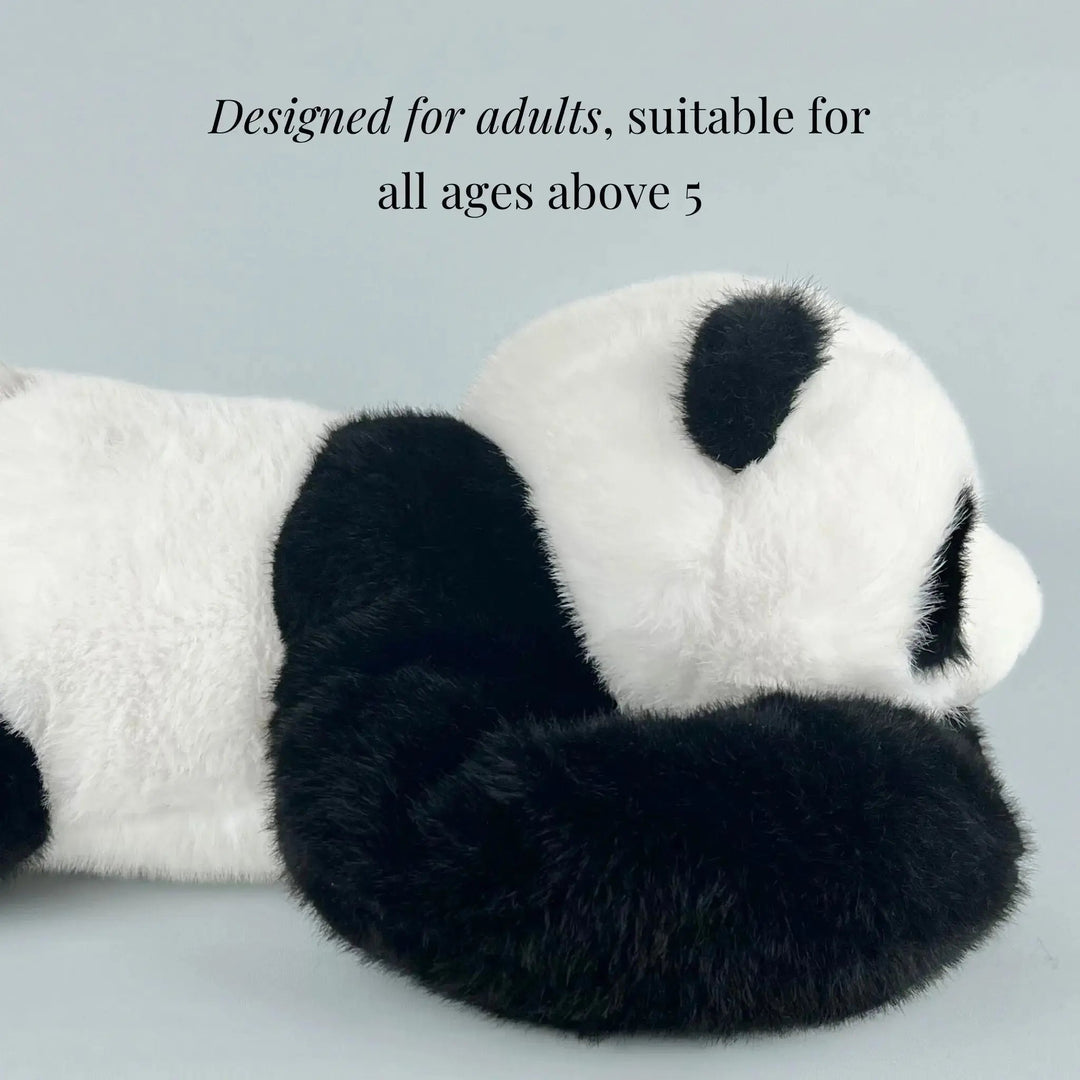 Side view of the panda plush lying flat, showing its fluffy white body, black ear and long black arm curled forward. 6