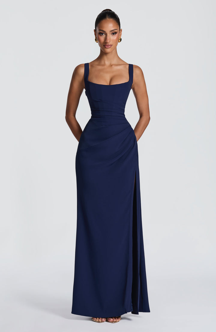 Navy Camille Maxi Dress front view with the slit starting at the thigh and gold heels.