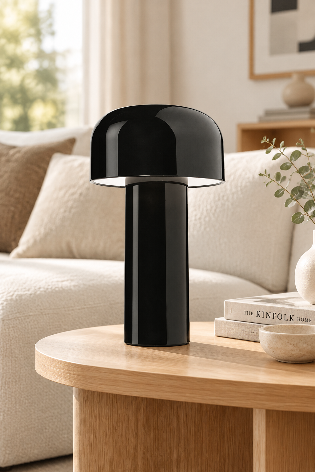 Glossy black mushroom lamp on a wooden side table next to cream sofa cushions and a plant 30