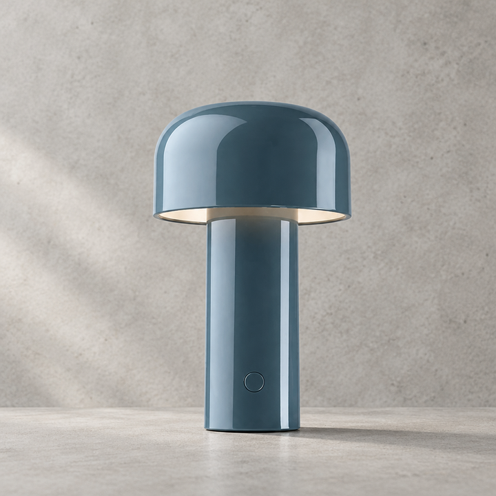Glossy blue-gray lamp with dome shade and round touch button, standing against a concrete wall 30