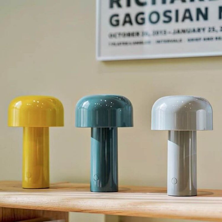 Yellow, teal and light gray mushroom lamps lined up on a wooden shelf under a framed poster 11