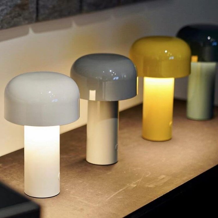 Row of lit mushroom lamps in white, gray, yellow and dark colors on a wooden shelf 19