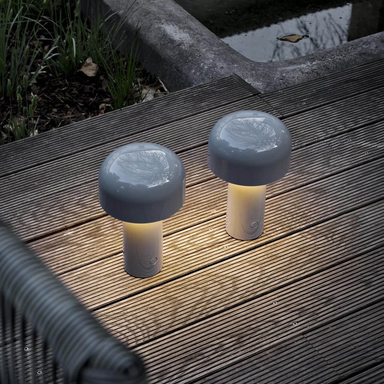Two gray mushroom-shaped lamps glowing warmly on a weathered wooden outdoor deck at dusk 21