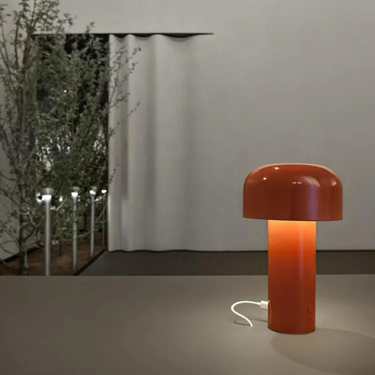 Glossy orange-red mushroom lamp lit on a table, with a white charging cable plugged into its base 24