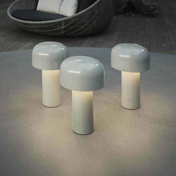 Three light gray lamps glowing on an outdoor concrete table near a woven lounge chair 7
