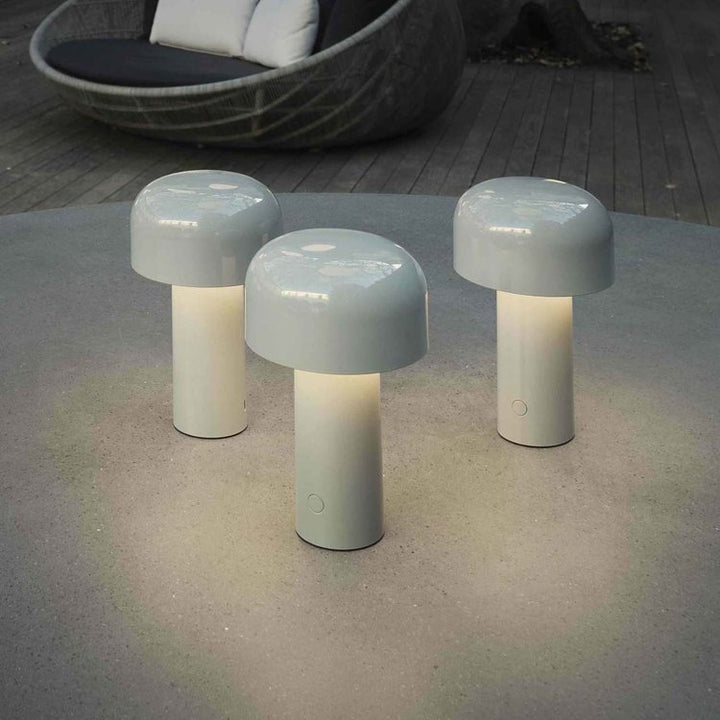Three light gray mushroom lamps glowing on an outdoor stone table near a woven lounge chair 7