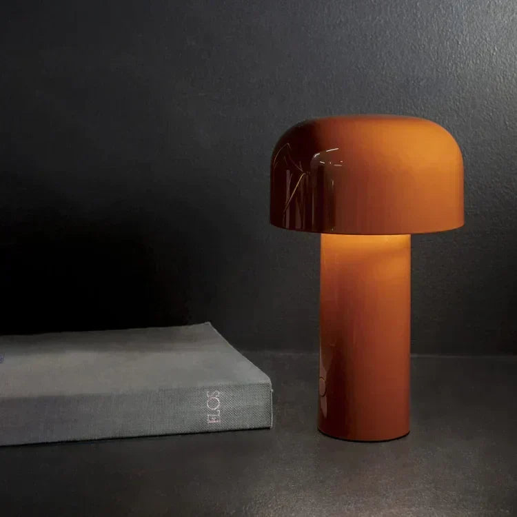 Lit burnt-orange mushroom lamp on a dark surface next to a gray hardcover book 8