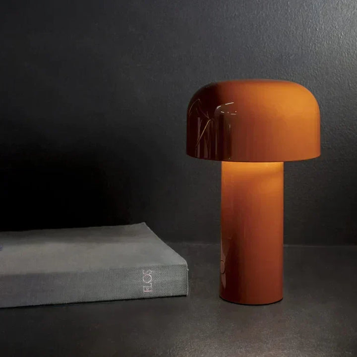 Glowing burnt orange mushroom lamp on a dark surface next to a gray book 8