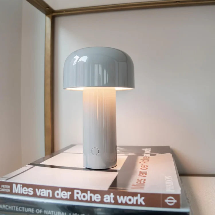 Lit gray mushroom lamp standing on a stack of art books on a shelf 10
