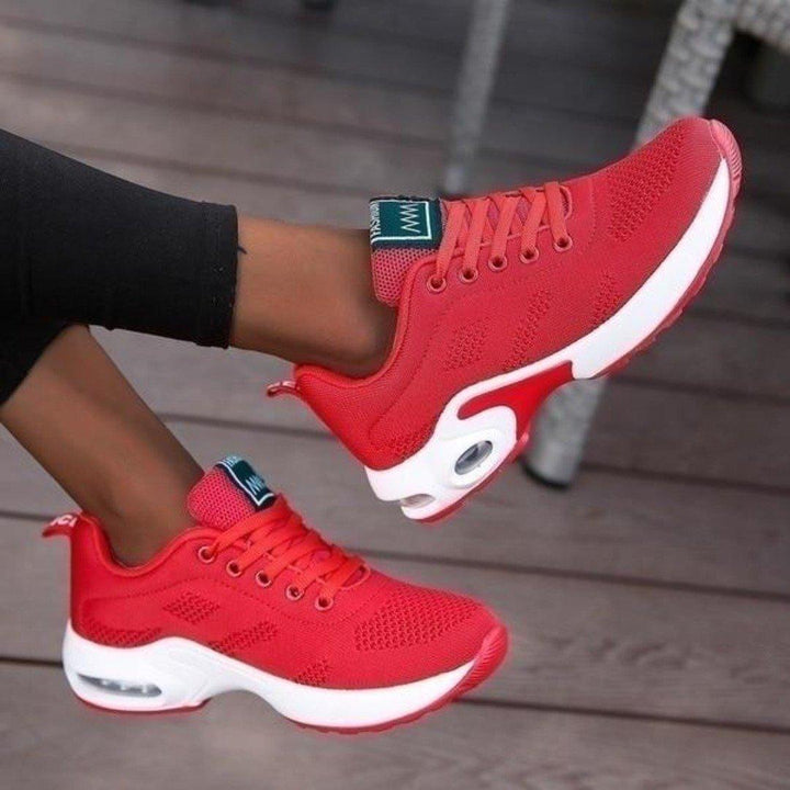 another view of red mesh lace-up sneakers with white air-cushion soles.