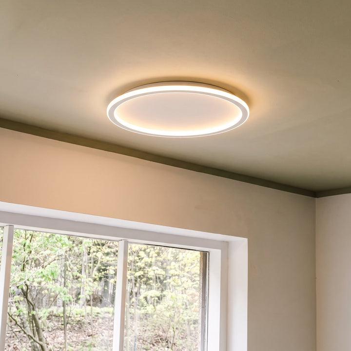 White ring ceiling light mounted above a window with white frame