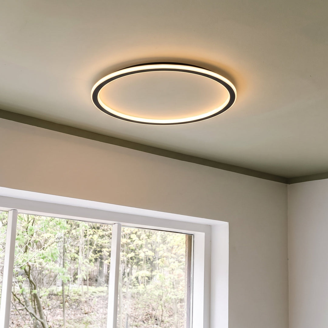 Lit ring ceiling light seen from below at an angle, mounted on a ceiling next to a white-framed window. 8