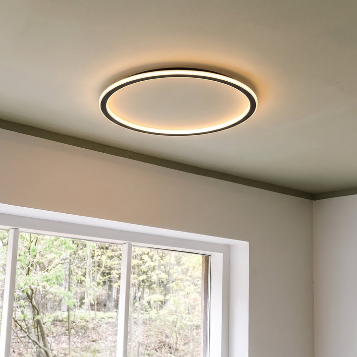 Lit ring ceiling light seen from below at an angle, mounted on a ceiling next to a white-framed window. 8