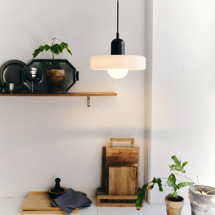Bauhaus Colored Glass Pendant Light with a glowing white glass shade and a black cap in a kitchen