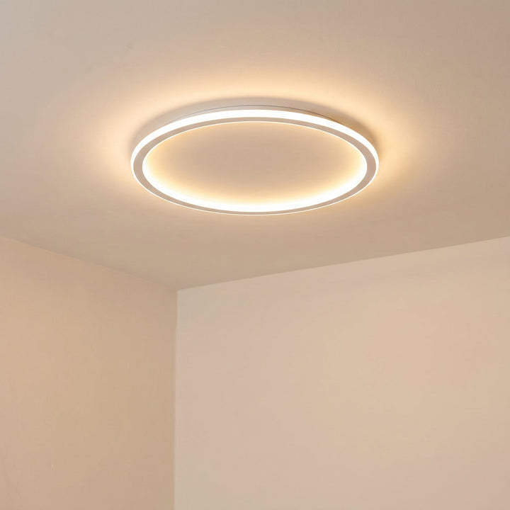 Another view of the lit white ring ceiling fixture on a peach-toned ceiling