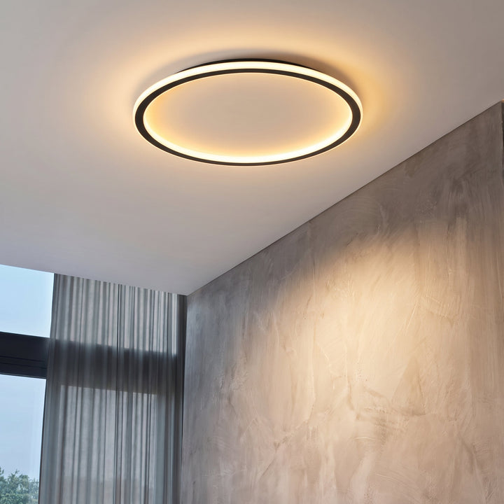 Lit ring ceiling light in a room corner with a textured plaster wall and sheer curtains beside a window. 3