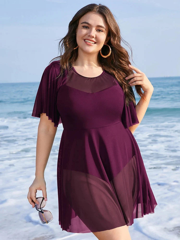 Frau am Strand in lila Strandkleid, Plus-Size, Sommermode, Meereshintergrund, lächelnd.