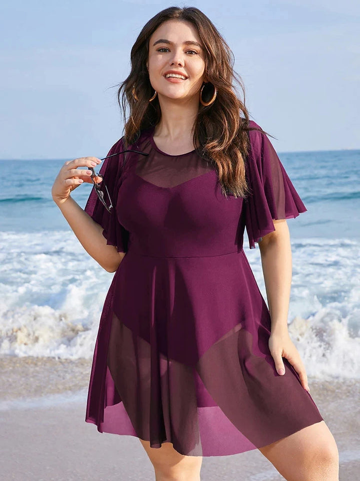 Frau im lila Strandkleid am Meer, Plus-Size, Sommermode, transparentes Design, Urlaubskleidung.