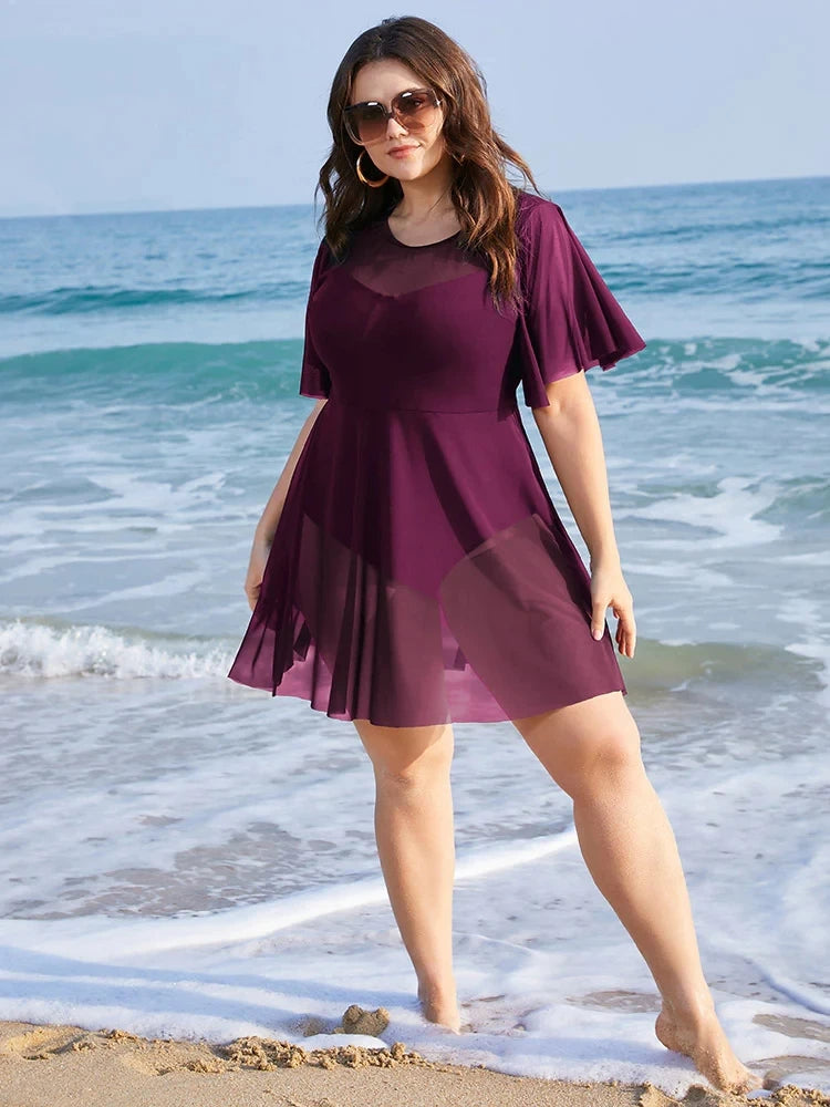 Frau im lila Strandkleid am Meer, Sommermode, Plus-Size, Sonnenbrille, Strandurlaub