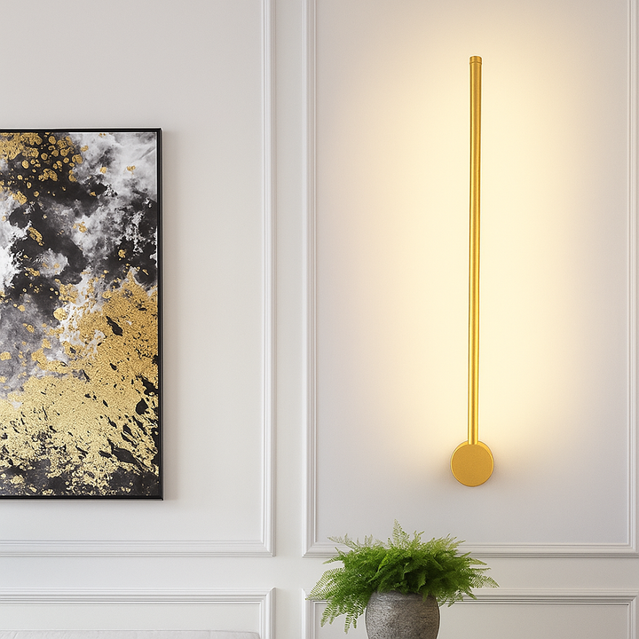Gold linear wall light detail with a round base disc at the bottom.