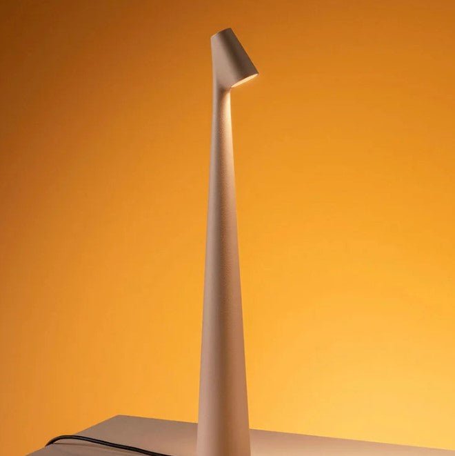 Detail of a cream rechargeable LED table lamp glowing against an orange backdrop.