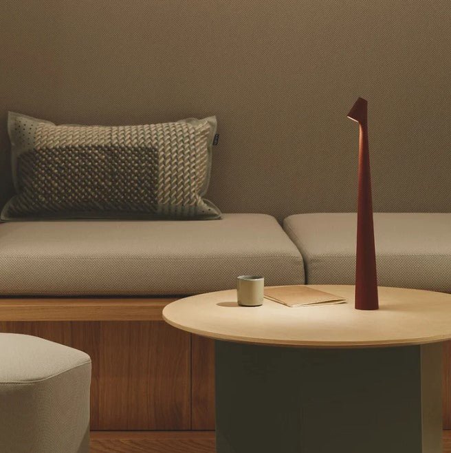 Another view of a red-brown rechargeable LED table lamp on a round light wood table.