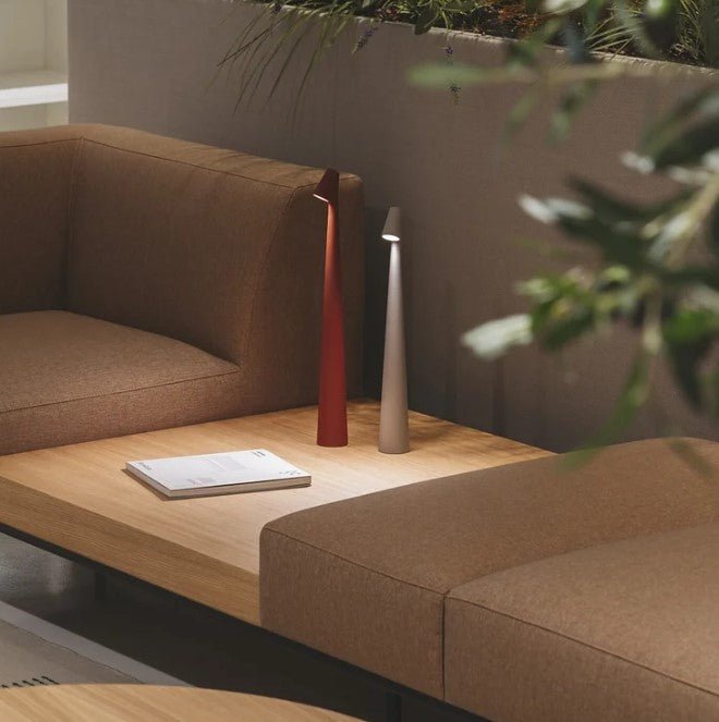 Another view of red and taupe rechargeable LED table lamps lit together on a wooden table.